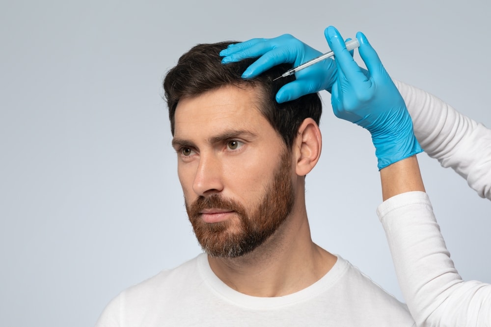 Man receives PRP injection in conjunction with his hair restoration therapy plan to improve his hairline.