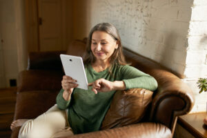 Middle-aged woman watching plastic surgery videos on a tablet at home