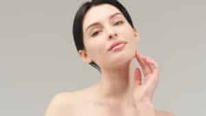 Close-up of a woman with smooth skin and a defined jawline gently touching her chin