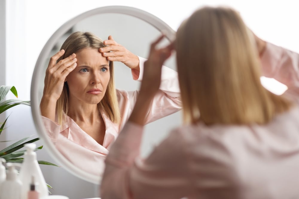 Woman looking int he mirror and examining her fine lines