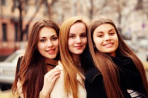 Group of three women smiling outdoors in the fall after a rhinoplasty reveal.